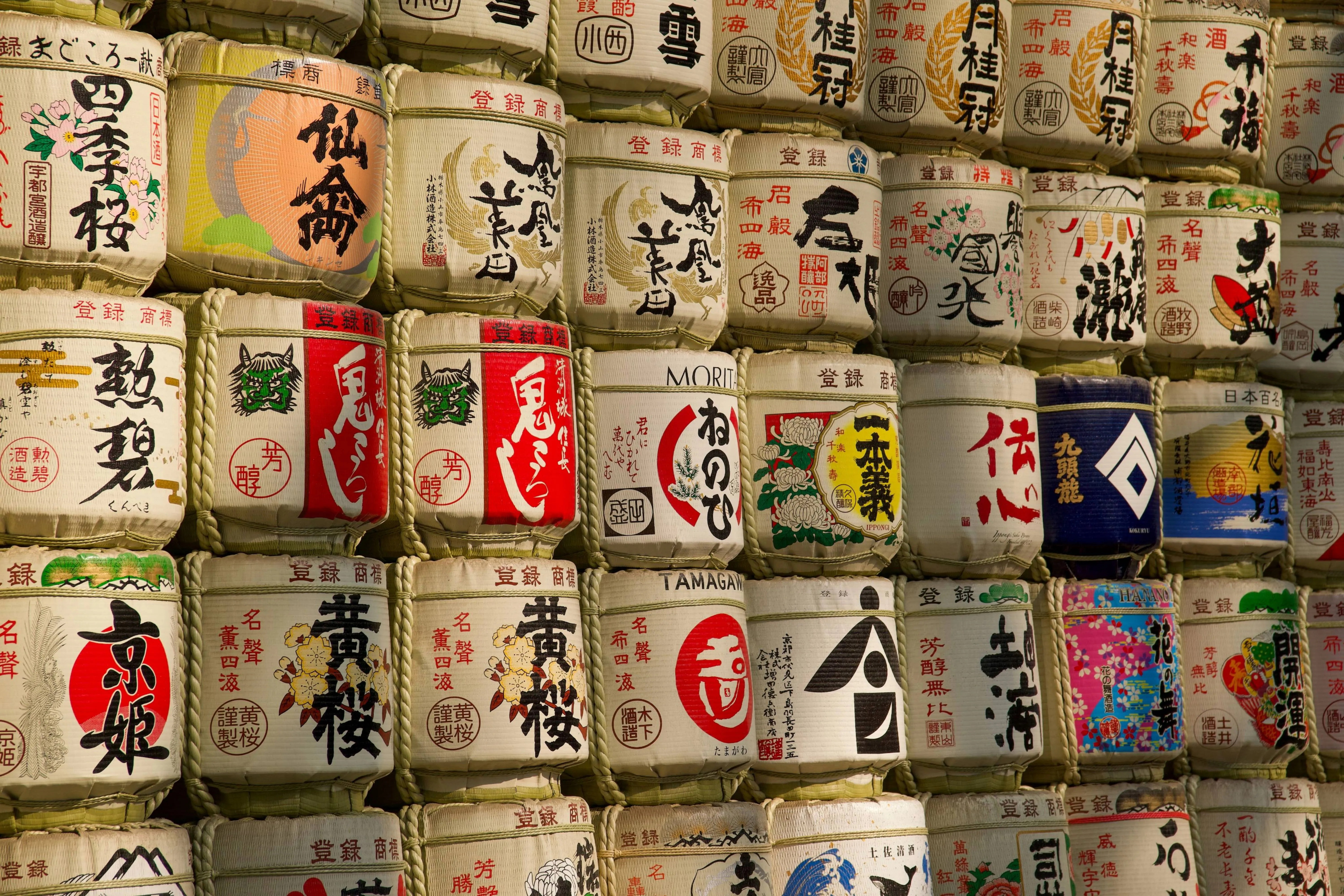 Stacked sake barrels wrapped in straw with Japanese calligraphy