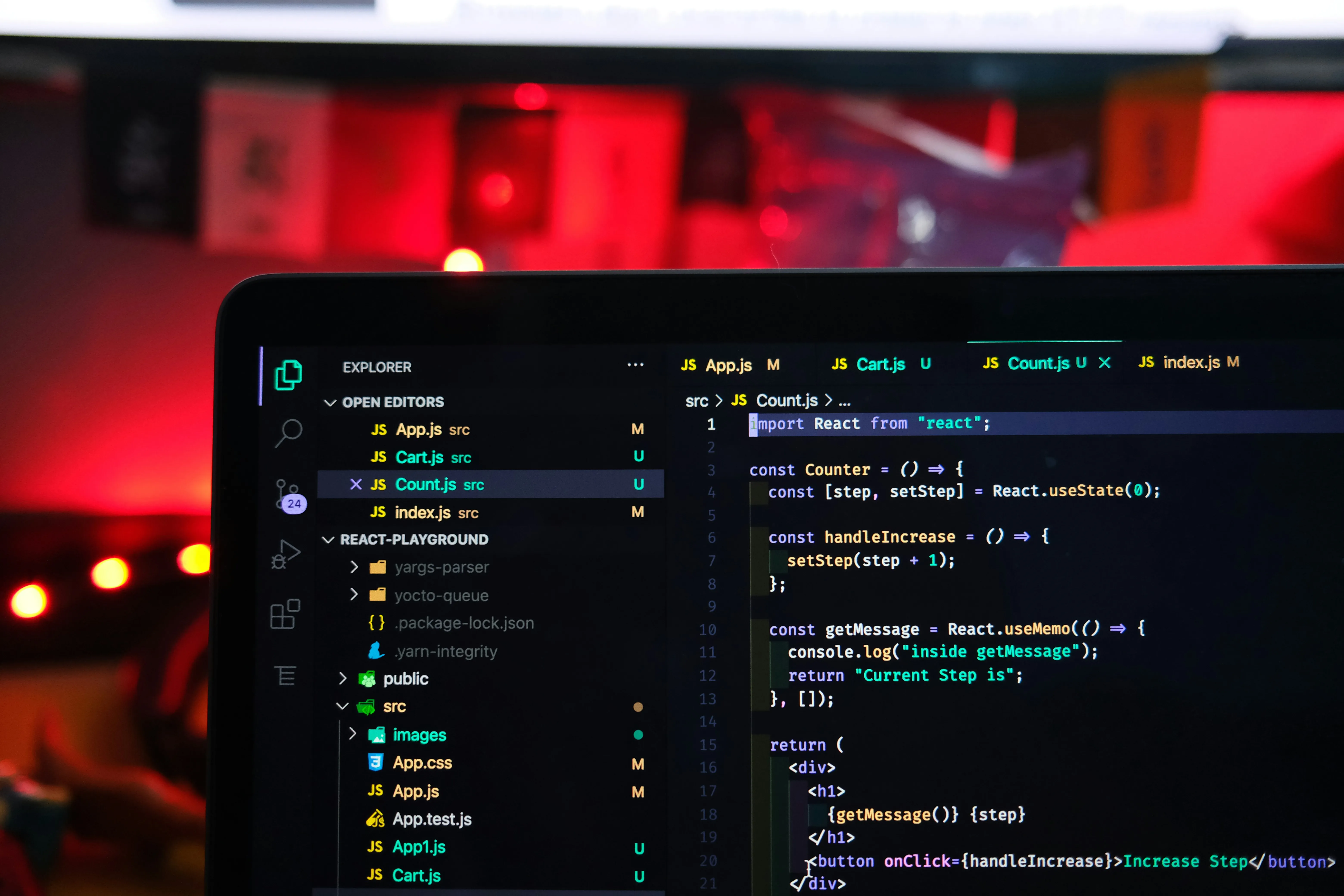 Laptop screen showing React code in a dark editor