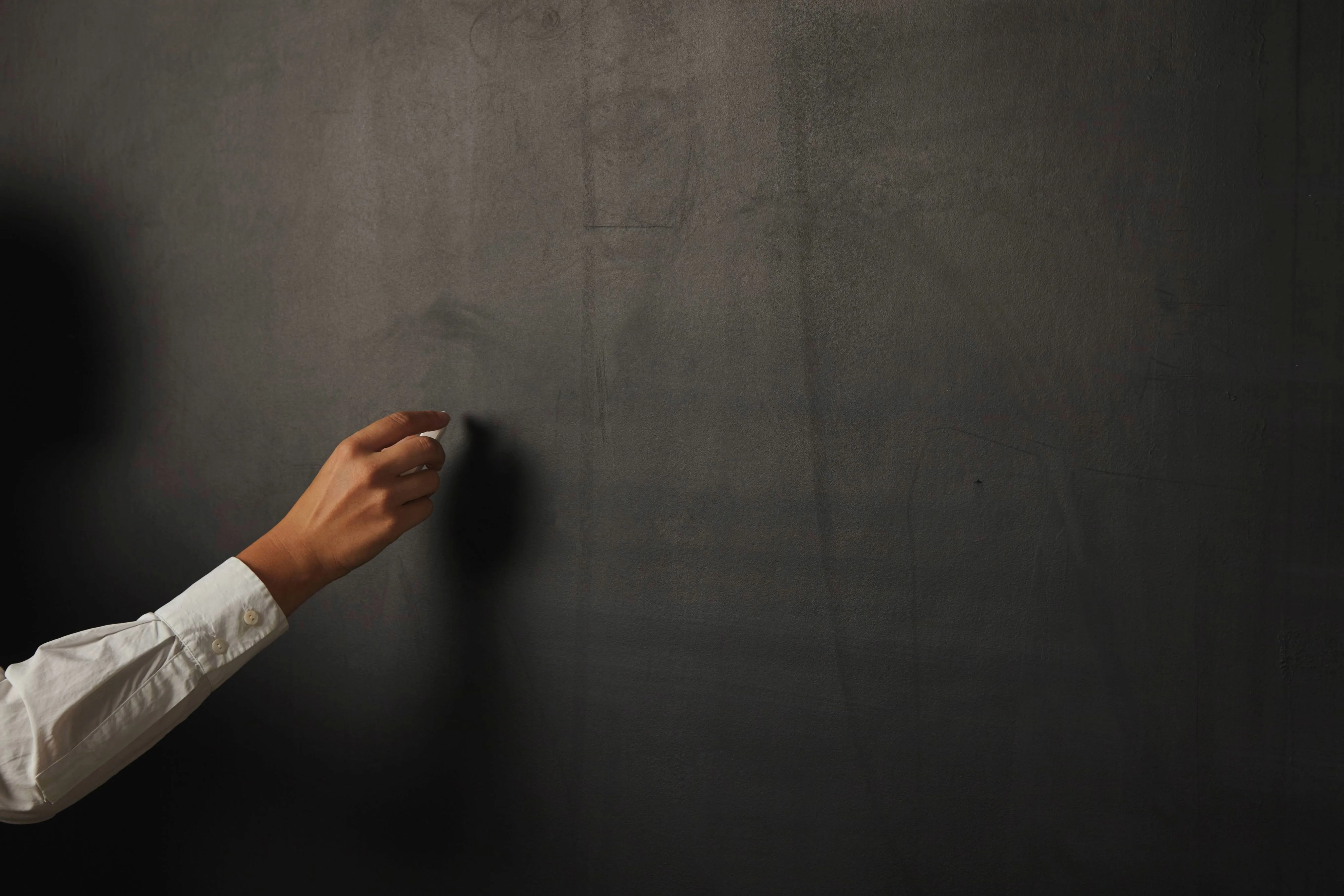 Hand holding chalk against a blackboard